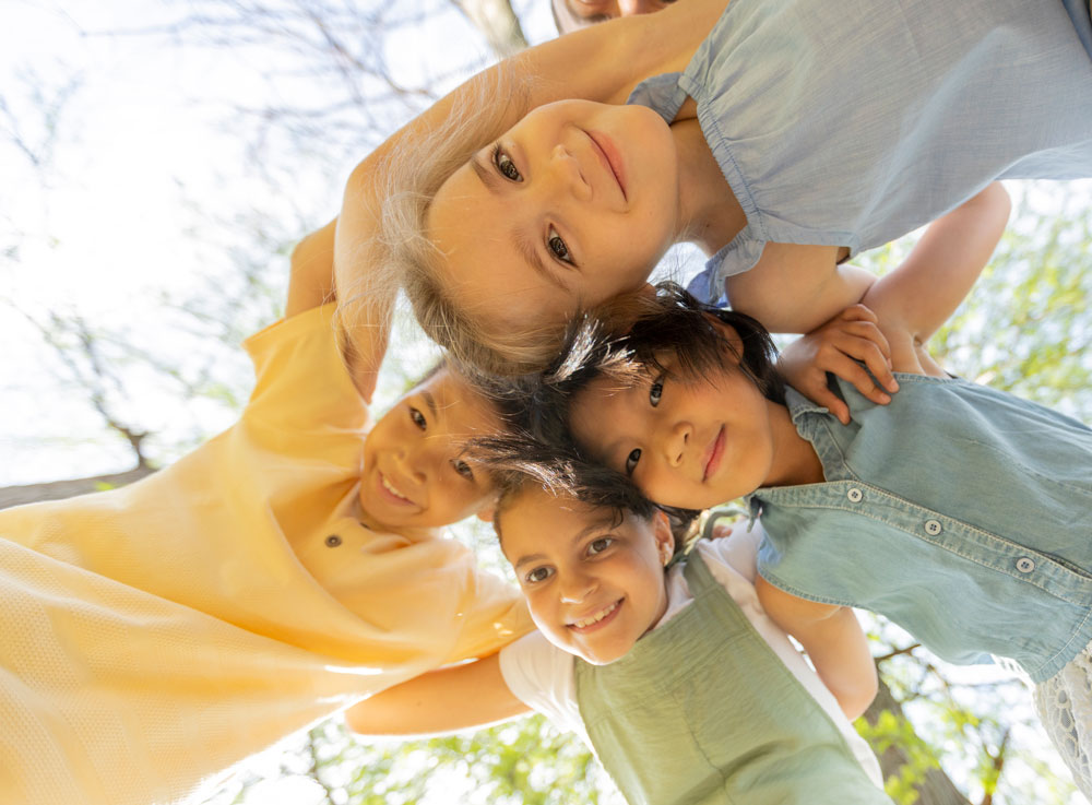 Multicultural children huddled with arms around each other